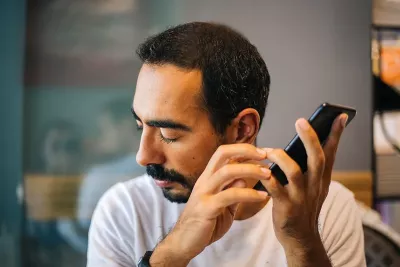 a male person with dark hair holding a smartphone using a screen reader.