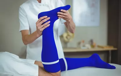 A massage therapist holds the foot of a client who is lying prone.