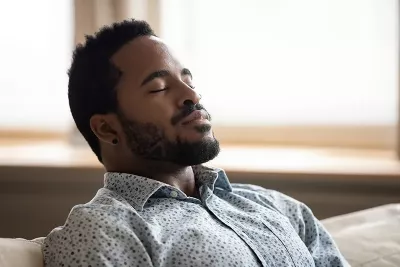 An African American man leans back and takes a deep breath.