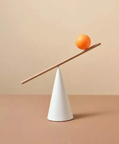 an orange ball balancing in a stick balancing on a cone. 