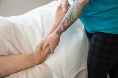 a massage therapist applying parallel fiction with her thumb and hand to a client's forearm.