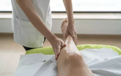 A massage therapist works on a client's lower leg.