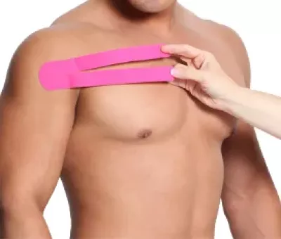 Without adding tension, setting hot pink kinesio tape along the clavicles of a shirtless male client.