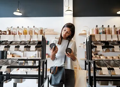 A woman holds two jars of products and compares the two.