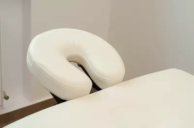 A white headrest on an empty massage table.