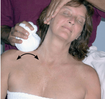 an MT demonstrates the rolling technique with a hot compress along a female client's neck area.
