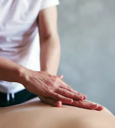 A practitioner lays hands on a client.