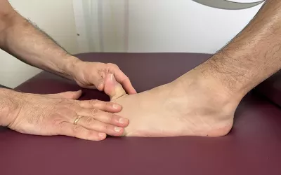 A massage therapist stretches the big toe upward while holding the rest of the foot down..