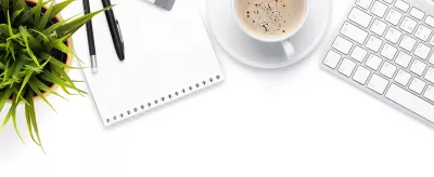 Note pad, cup of coffee, computer keyboard.