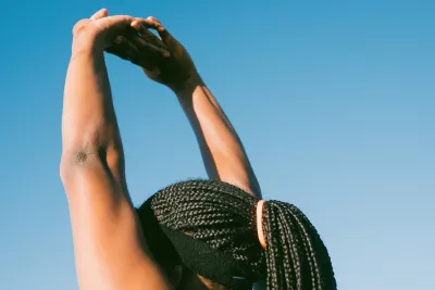 Black woman stretching arms above her head.