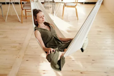 A woman lays in a hammock indoors.