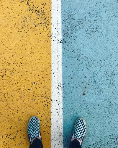 Conceptual, feet standing on divided road, half blue, half yellow