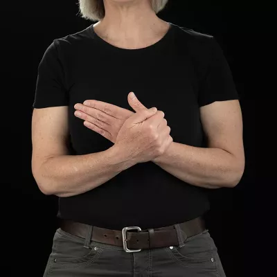 Demonstrating step 2 of stretching the first metacarpophalangeal joint with hands in front, palms facing the chest rocking the palm back and forth.