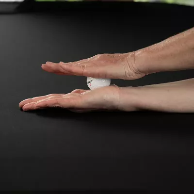 Demonstration of using a golf ball between the two palms of the hands to massage the hand muscles.