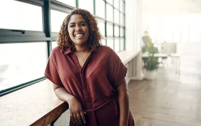 A smiling woman leaning on a countertop.