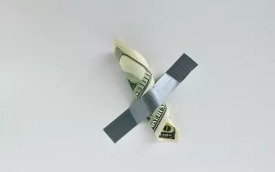 A $100 bill is taped to a wall.