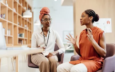 Two women are seated in conversation.