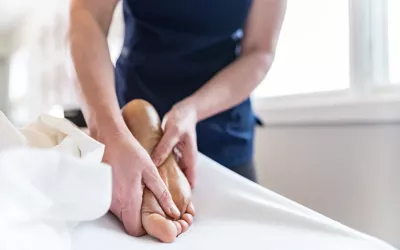 A Massage therapist massaging bottom of client's foot.