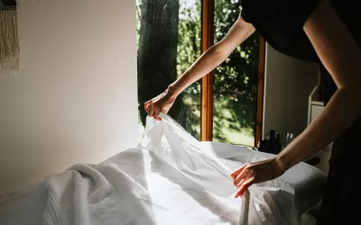 A massage therapist puts sheets on a massage table.