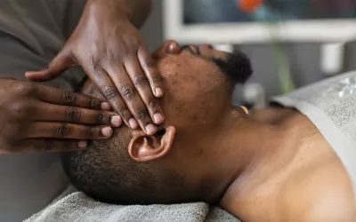 A massage therapist massages the side of a client's head.