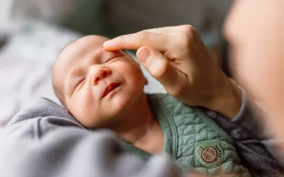 A practitioner delivers craniosacral therapy to a baby but touching the baby above its eyebrow.