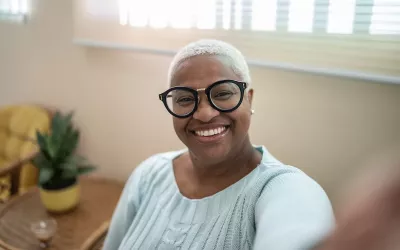 A seated woman with glasses smiling at the camera.