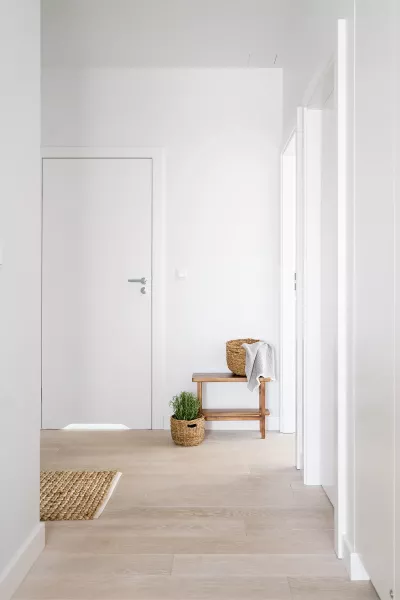 A hallway in an office leading to a small table with a towel and a door.