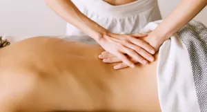 A massage therapist works on a client's lower back.