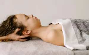 A practioner works on the back of the head of a client who is supine on a table.