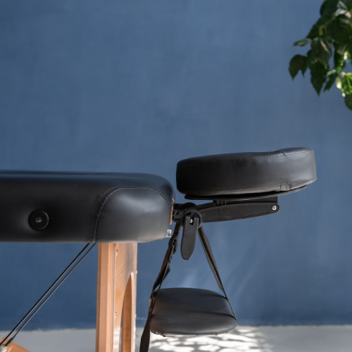 a black massage table with head cradle in an empty rooom