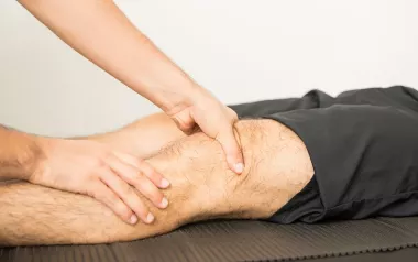 A massage therapist works on a client's knee area.