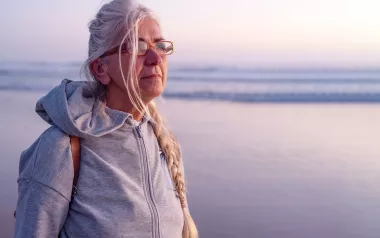 An elderly lady looks out across an ocean.