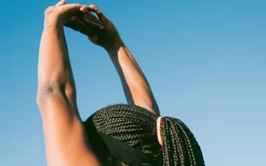 Black woman stretching arms above her head.