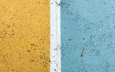 Conceptual, feet standing on divided road, half blue, half yellow.