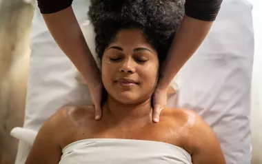 Massage therapist applying massage strokes to female client on massage table.