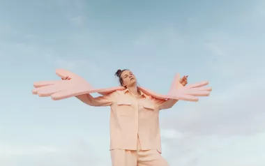 A woman holds giant foam hands that symbolize self-care and empathy.