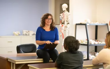 An instructor chats with people in an anatomy classroom.