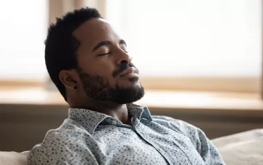 A Black man leans back and takes a deep breath.