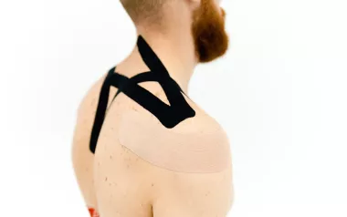 Kinesiology tape applied to a person's back and shoulder.