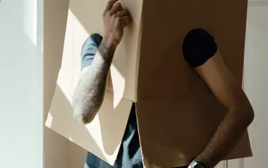 A person wearing a moving box over their head ponders change.