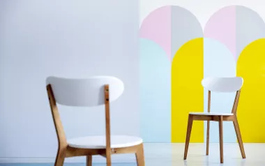 two white chairs seated in a pastel colored room full of light.