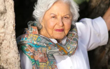 portrait of deborah szekely in her 80s. She's wearing a colorful scarf.