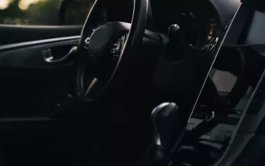 a steering wheel and a black drivers seat interior of a car. 