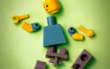 A LEGO figure of a person with all the parts unattached and scattered.