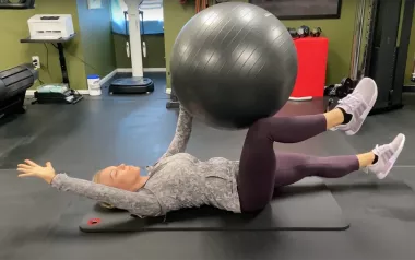 Author Marisa Savino uses a fitness ball for stability during an exercise.