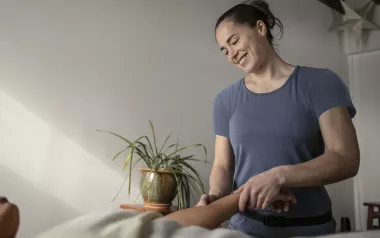 A massage therapist smiles while performing acupressure.