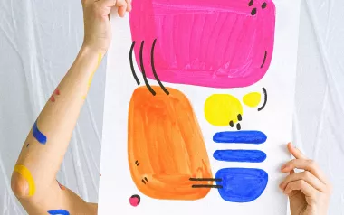 Person holding up a sheet of paper with abstract art in front of their face.
