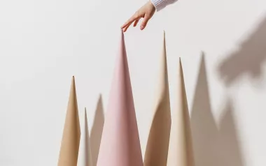 A person puts the tip of their finger on the pointy top of a cone with other cones around.