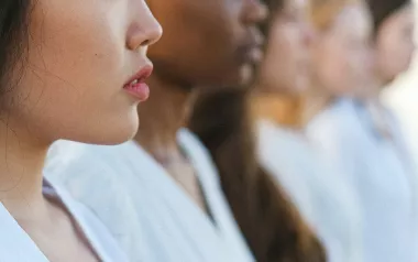 A line of women of all different skin tones, colors, and hair styles, facing to the right.