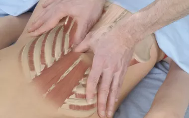 Two hands treating the lumbar paraspinal muscles.